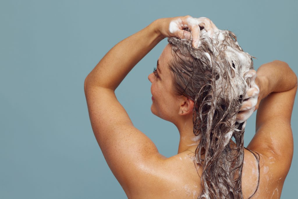 Vrouw masseert shampoo in haar hoofdhuid met haar vingertoppen