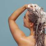Vrouw masseert shampoo in haar hoofdhuid met haar vingertoppen