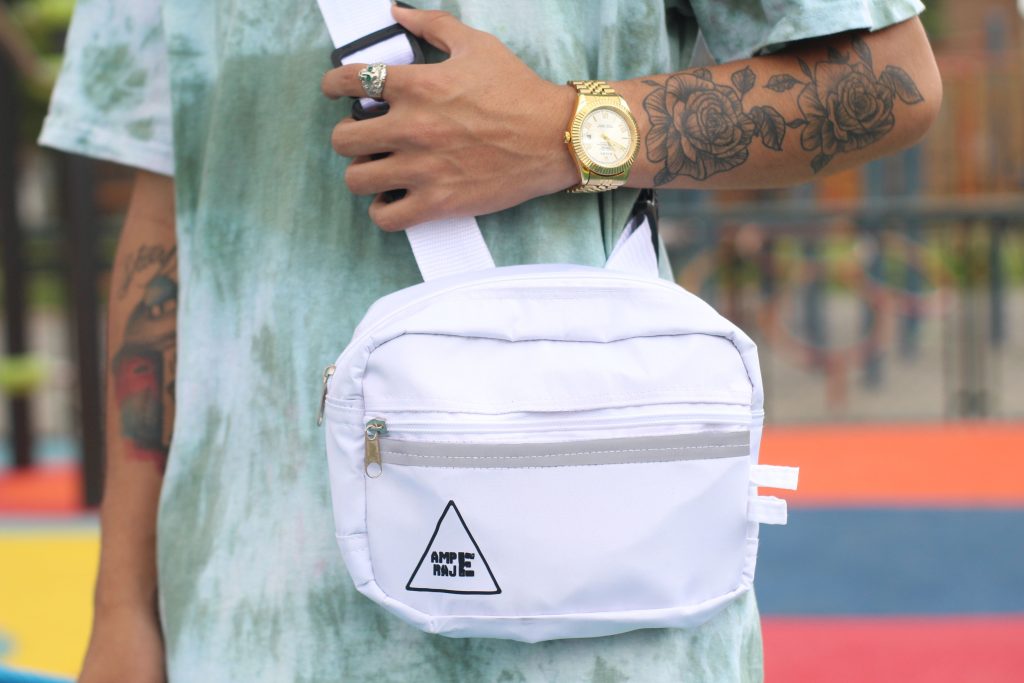 Hand houdt een witte crossbody tas met brede band vast