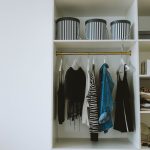 Opgeruimde kledingkast met hangende kleding en opbergmanden