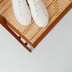 Schone witte sneakers op een rieten stoel