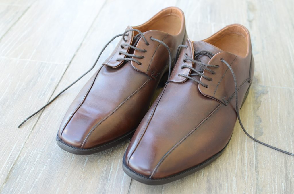 Nieuwe bruine leren veterschoenen op een houten vloer