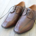 Nieuwe bruine leren veterschoenen op een houten vloer