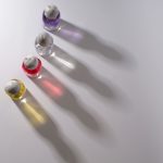 Vier parfumflesjes die gekleurde schaduwen werpen