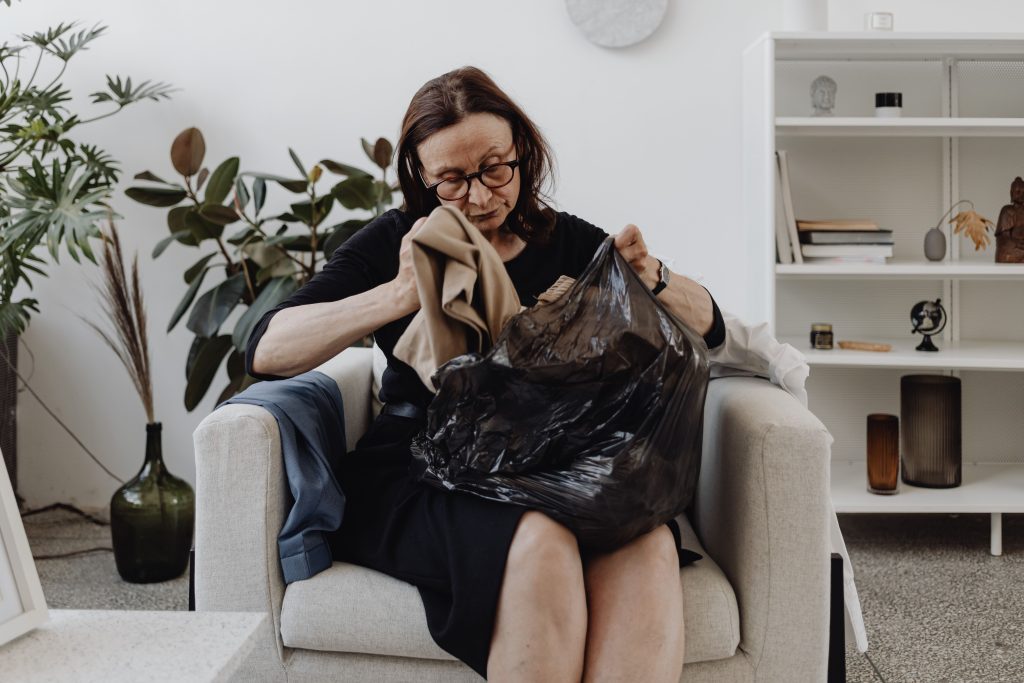 Vrouw sorteert kleding uit een zak in haar woonkamer